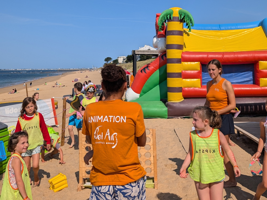 Animateur et enfants sur le sable près de structures gonflables