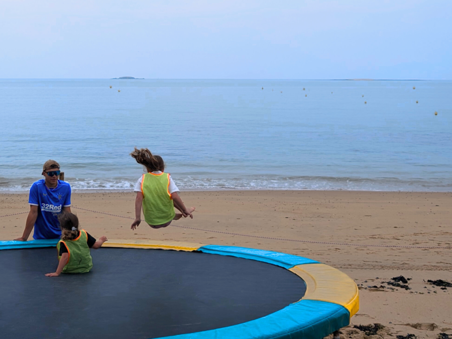 Enfants qui sautent sur un trampoline vue mer