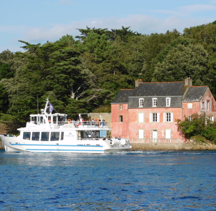 Bateau en mer passant près d'une maison rose en bord de mer