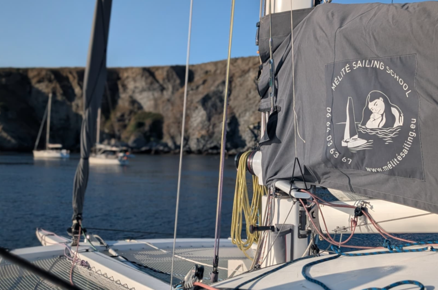 Photo de la côte, de la mer et de la voile portant le logo de mélité croisière