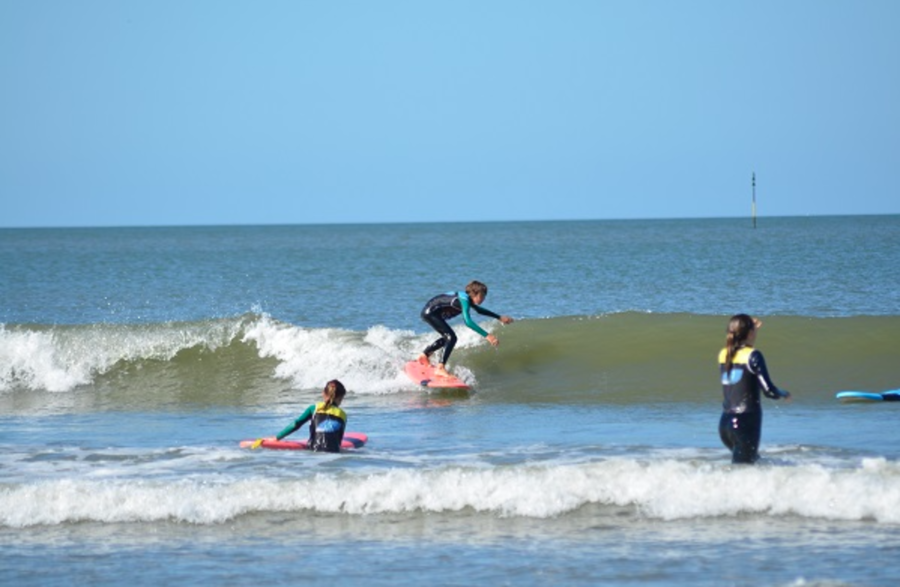 Enfants dans l'eau dont un qui surfe une vague