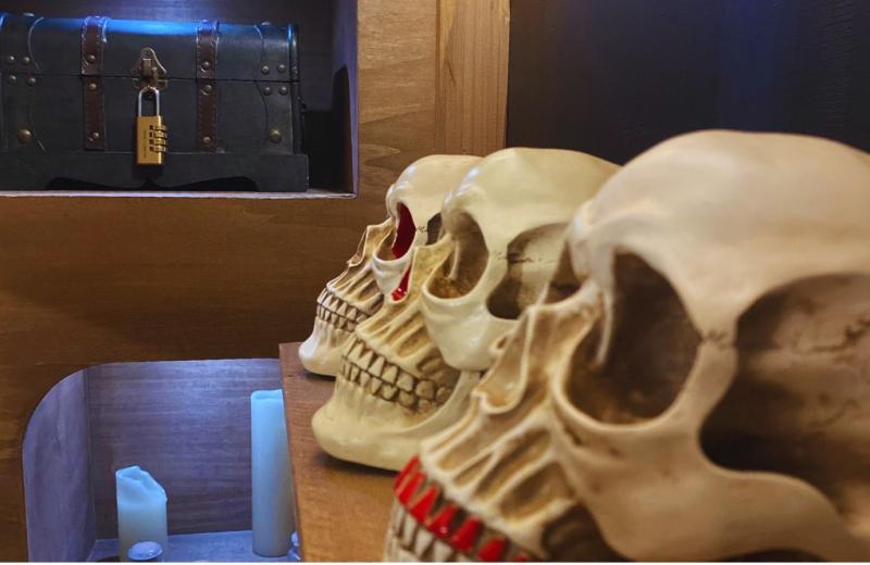 Décor d’escape game avec crânes et coffre verrouillé.