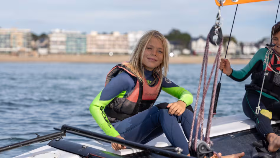 Petit garçon qui apprend à naviguer en catamaran avec le club de voile Yagga