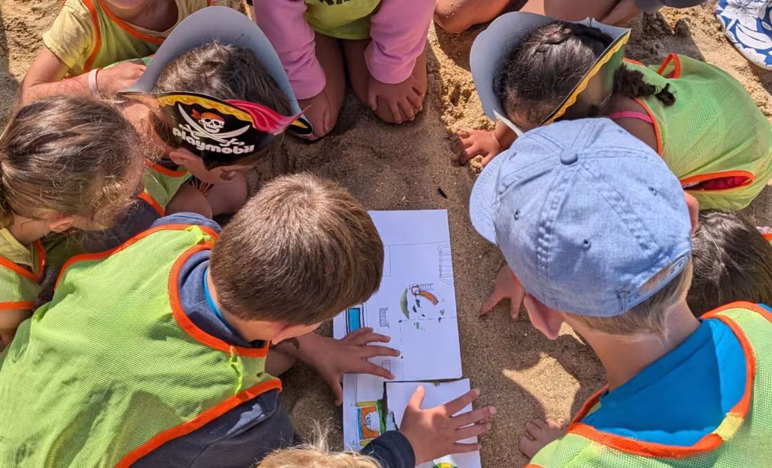 Enfants sur le sable qui regardent une carte