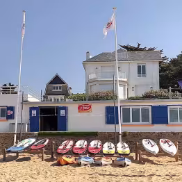 Photo de l'école avec paddles et kayaks sur la plage