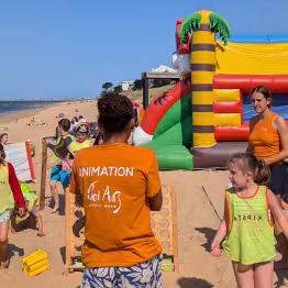 Animateur et enfants sur le sable près de structures gonflables