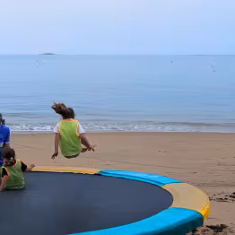 Enfants qui sautent sur un trampoline vue mer