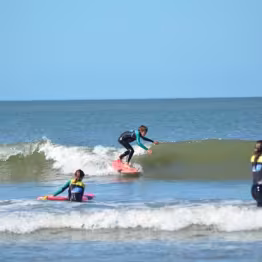 Enfants dans l'eau dont un qui surfe une vague