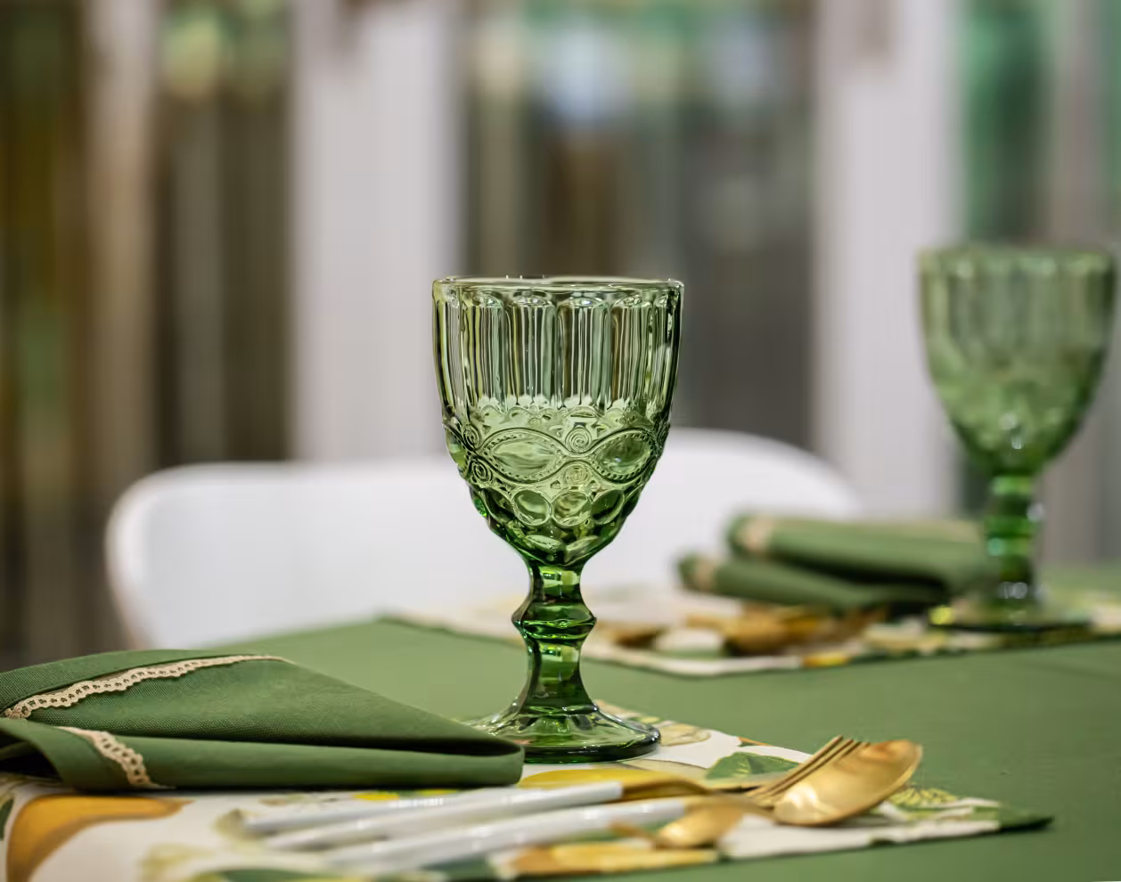 Idée de décoration de table pour un dîner avec des verres à pied en verre vert texturé
