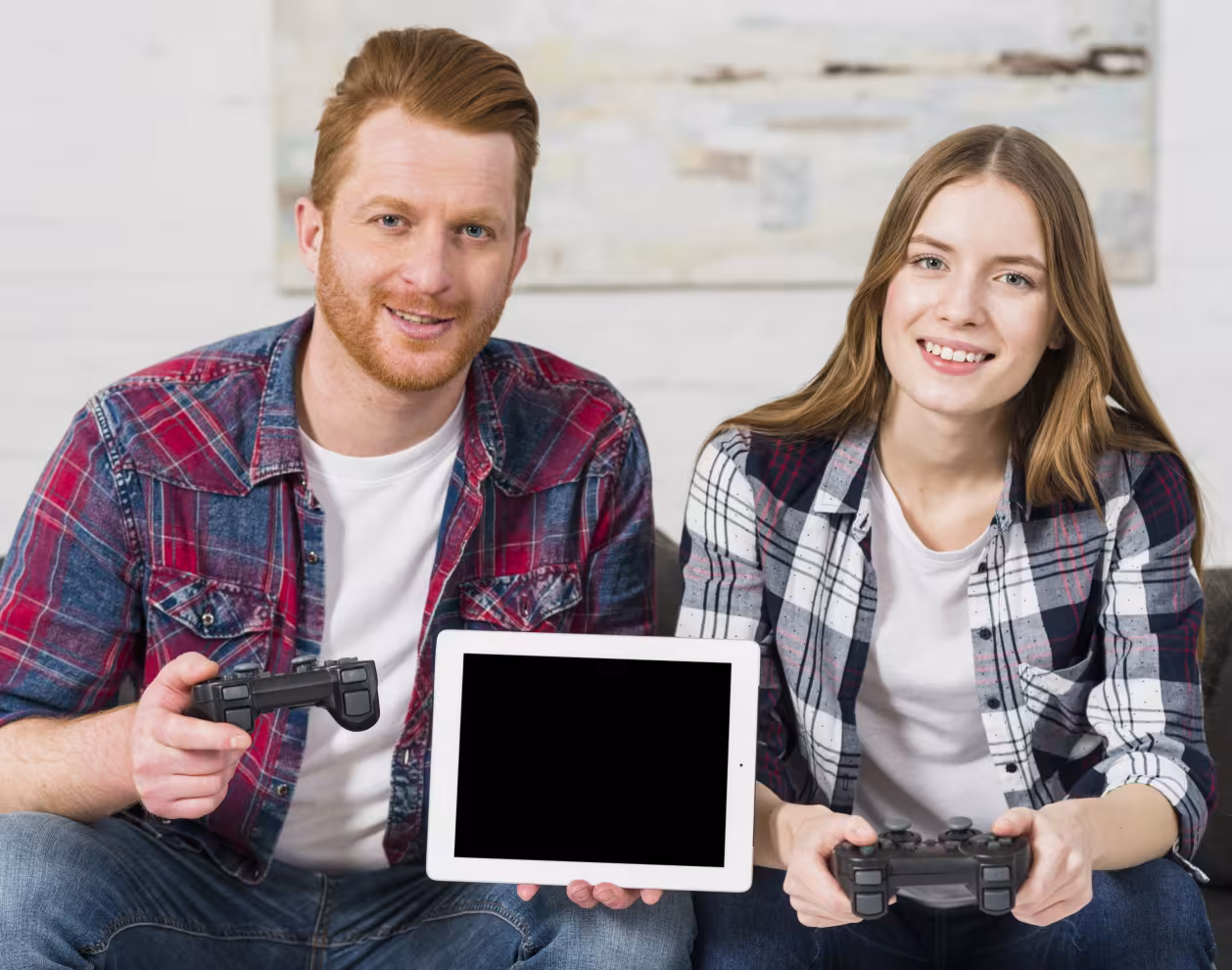 Un couple assis tenant une tablette et des joysticks