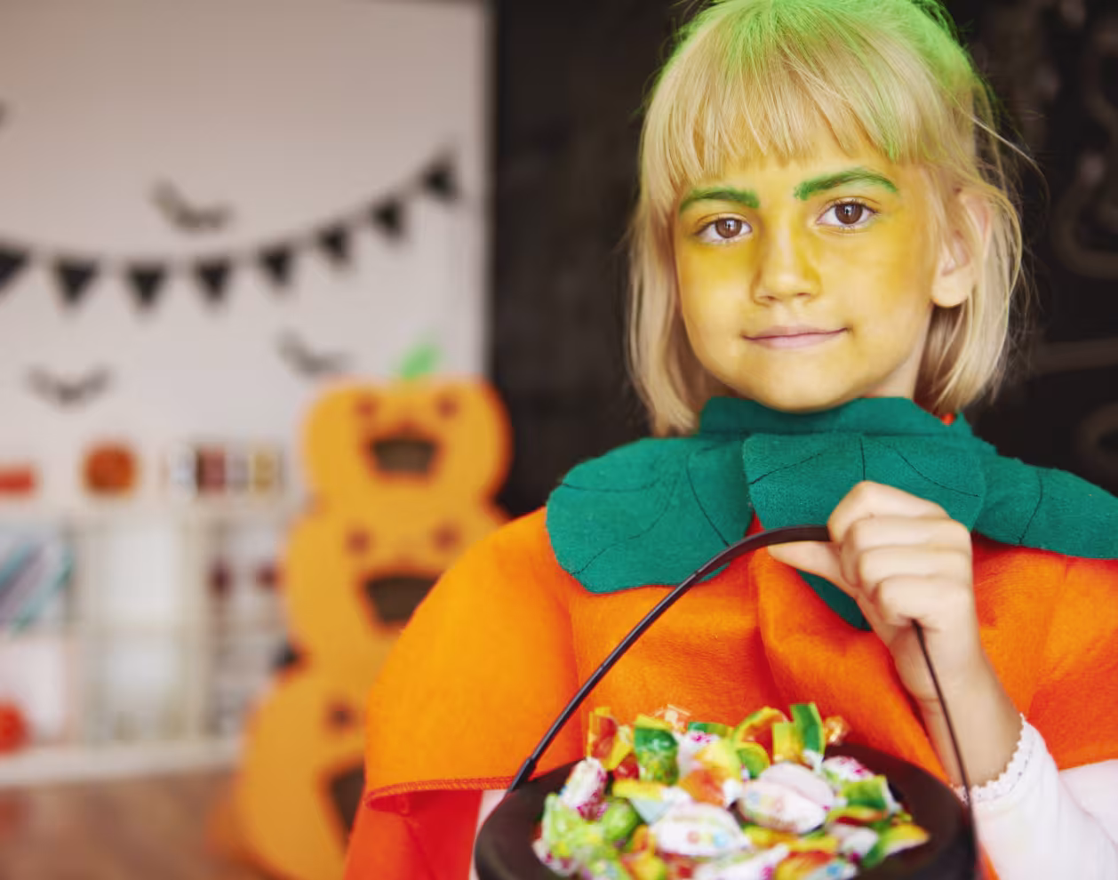 Fille en costume de citrouille avec un bol de bonbons